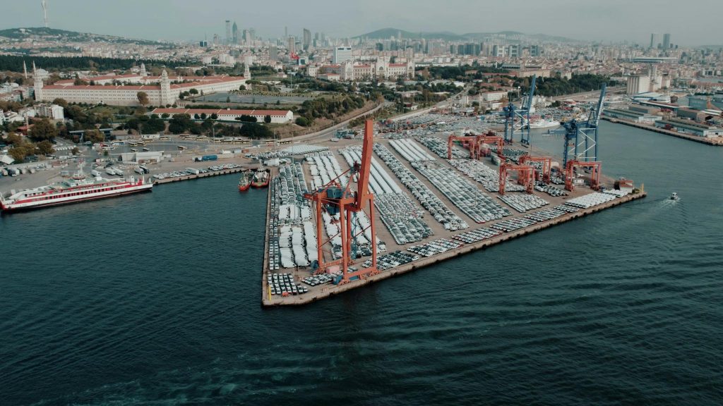 Aerial view of a busy cargo port in Istanbul with cityscape in the background, highlighting logistics and trade.